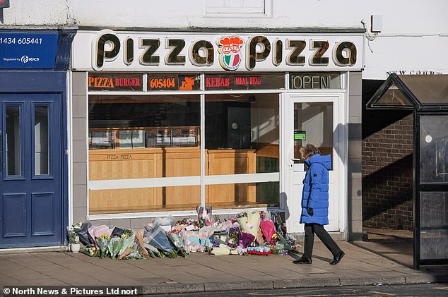 A member of the public walks past floral tributes that were laid at the scene of the murder