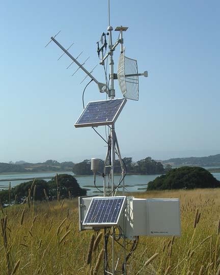 Station météorologique avec plusieurs instruments en champ près d'un lac