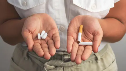 Jeune femme tenant des comprimés et une cigarette cassée.