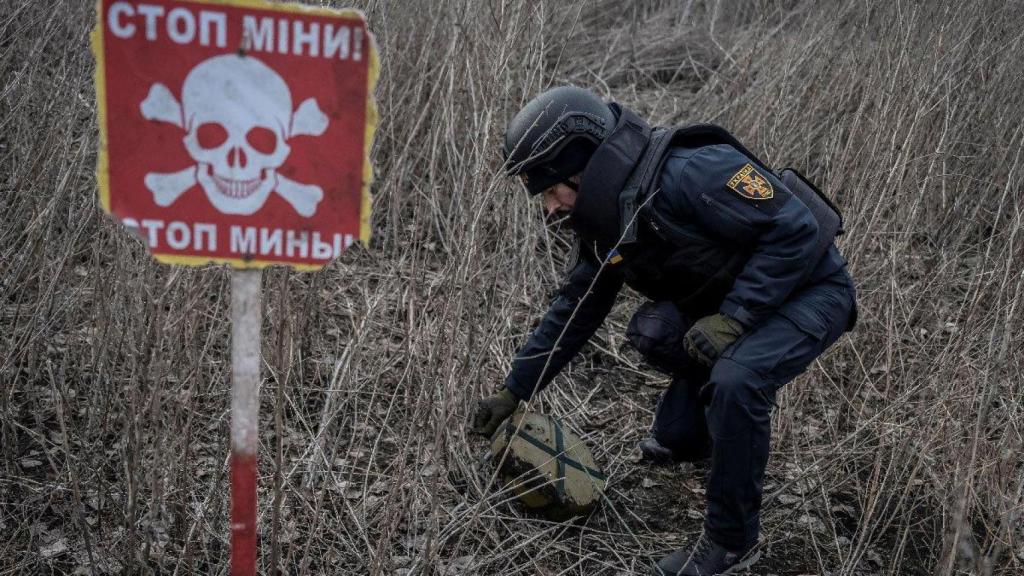 Un membre du Service d'État des Urgences de l'Ukraine inspecte une zone à la recherche de mines non explosées à Kharkiv en 2023.