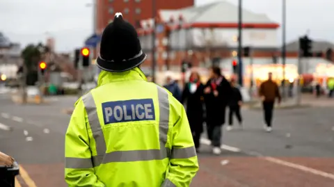 Un policier se tient près d'une route dans un centre-ville