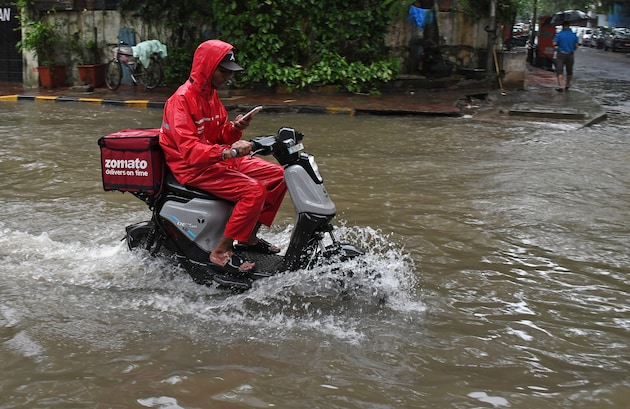 Un livreur Zomato en imperméable sur sa moto électrique.