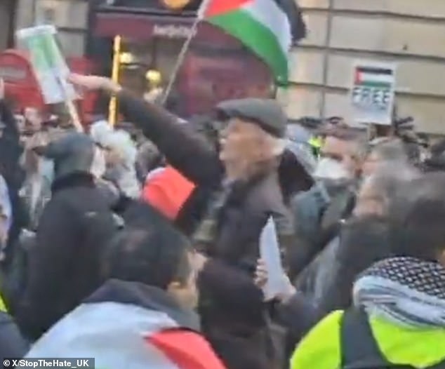 L'homme âgé portant un bonnet noir, une veste marron foncé, une écharpe marron et un sac à dos noir.