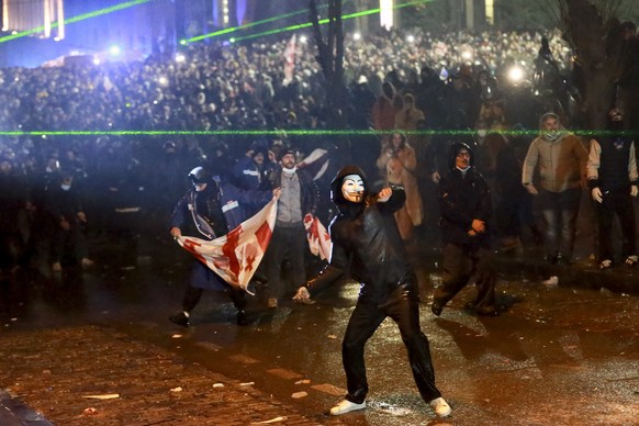 Un manifestant masqué lance un objet en direction de la police lors d'un rassemblement contre la décision du gouvernement de suspendre les négociations pour rejoindre l'Union européenne pendant quatre ans.