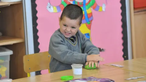 Kyran en classe, jouant avec de la pâte à modeler.