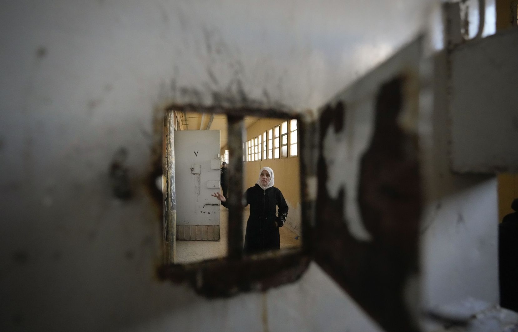 Une femme examine les cellules de la tristement célèbre prison militaire de Saydnaya, au nord de Damas, en Syrie, le lundi 9 décembre 2024.
