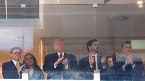 Des personnalités politiques applaudissant lors du match