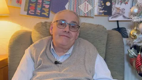 Gary Jameson dans un fauteuil avec des cartes d'anniversaire derrière lui