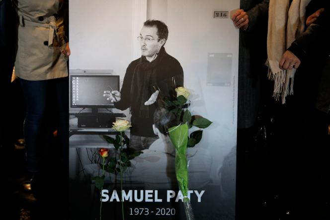 Des personnes tiennent une photo du professeur d’histoire Samuel Paty, lors d’une marche commémorative en son honneur, mardi 20 octobre 2020 à Conflans-Sainte-Honorine, au nord-ouest de Paris.