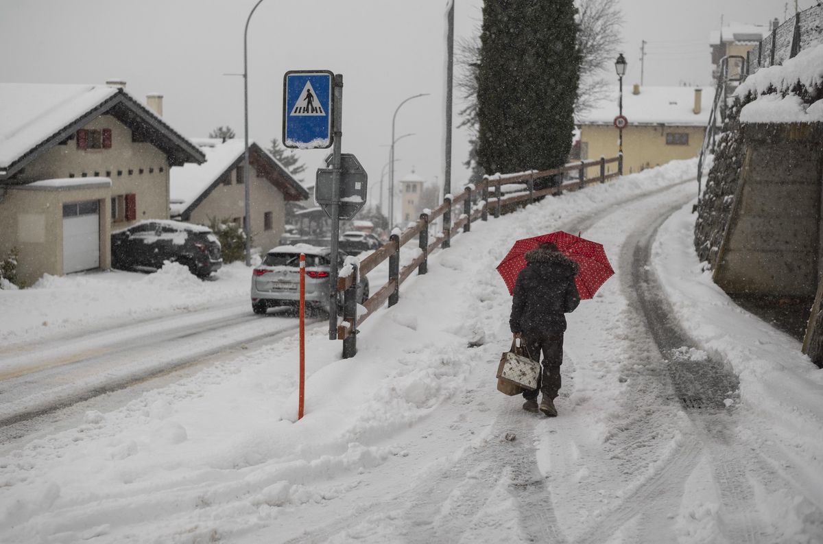 Une femme marche sur une rue enneigée à Ollon, Crans-Montana, le 23 décembre 2024.