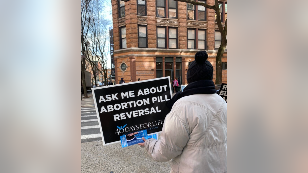 Une militante pro-vie tenant une pancarte sur le renversement des pilules abortives.