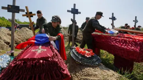 Soldats russes mettant des drapeaux sur les cercueils de soldats tués