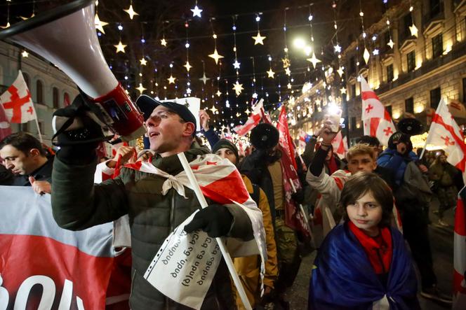 Des manifestants portant des drapeaux géorgiens marchent lors d’un rassemblement anti-gouvernemental à Tbilissi, Géorgie.
