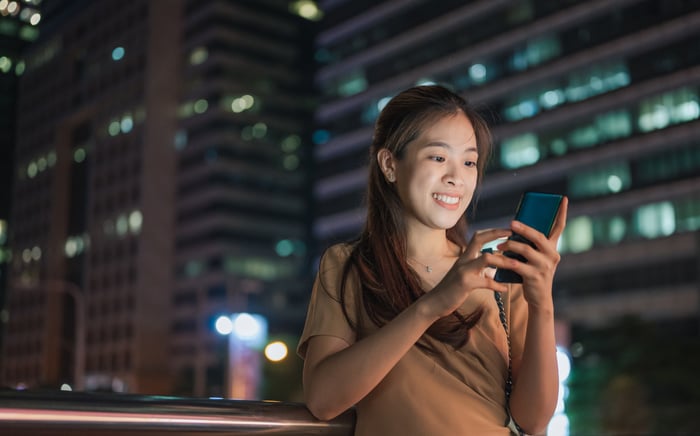 Investisseur se tenant dehors avec un téléphone mobile la nuit.