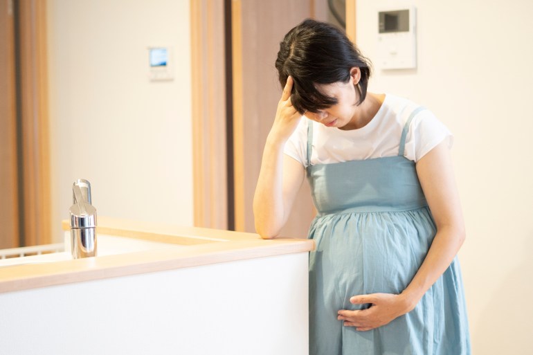 Femme enceinte souffrant d'un mal de tête dû aux nausées matinales.