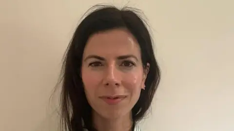 A woman - Dr Jay Watts - looking directly into the camera. You can only see her head and neck. She has dark brown hair and brown eyes.