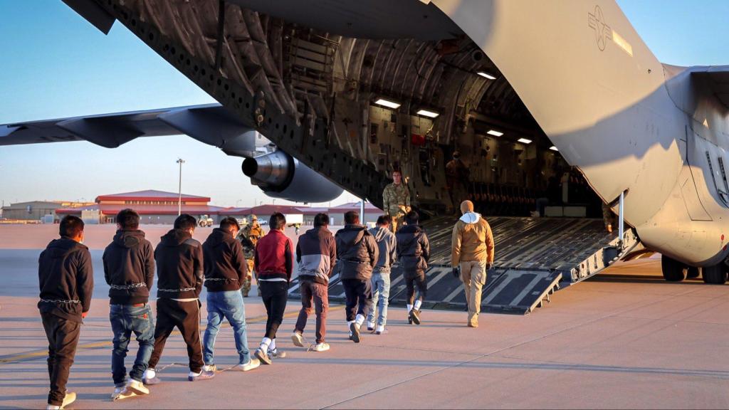 Migrants entrant dans un avion pour un vol de déportation