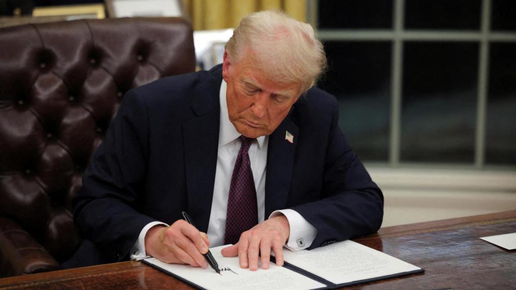 Donald Trump signant une ordonnance dans le Bureau Ovale à la Maison Blanche.