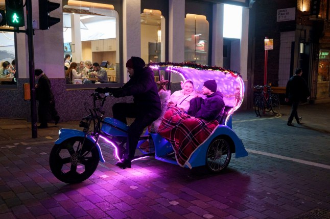 Des passagers à l'arrière d'un pedicab traversant Chinatown dans le West End de Londres, le 7 janvier 2025.