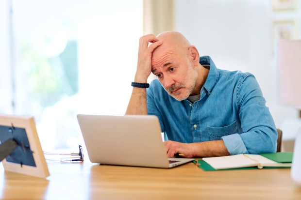 Homme préoccupé travaillant sur un ordinateur portable à la maison.