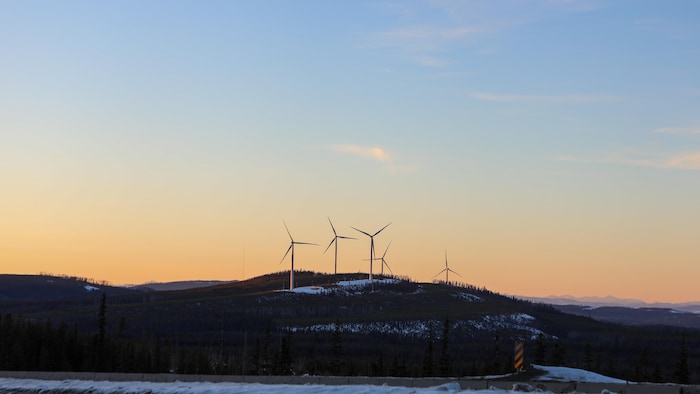 Cinq éoliennes sur une colline.