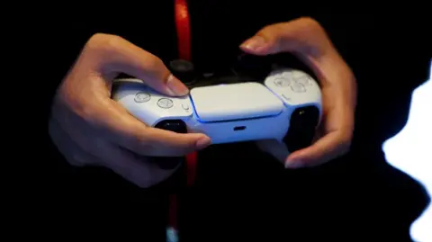 Un joueur tenant une manette PS5 blanche