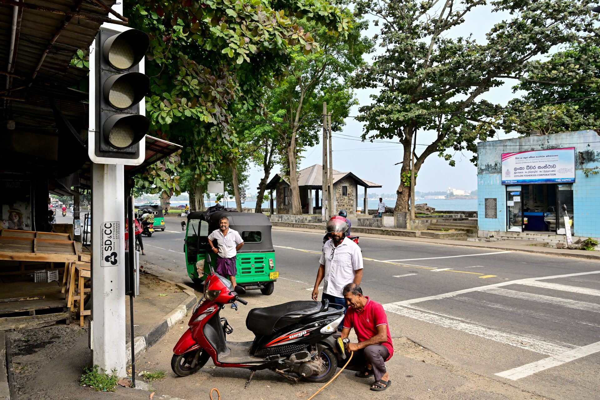 Sri Lankans stand beside an inoperative traffic light following a nationwide power outage in Galle