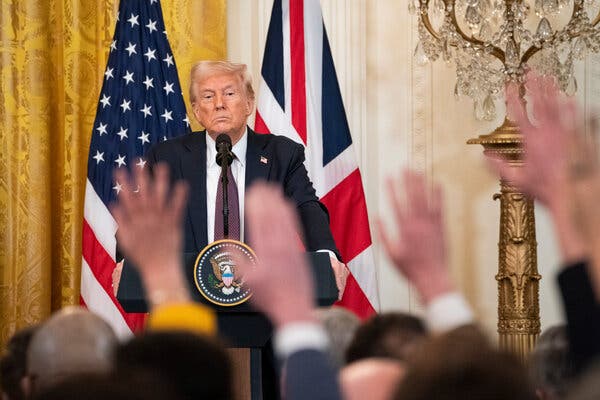 President Trump standing behind a lectern in front of an American and British flag in the White House.