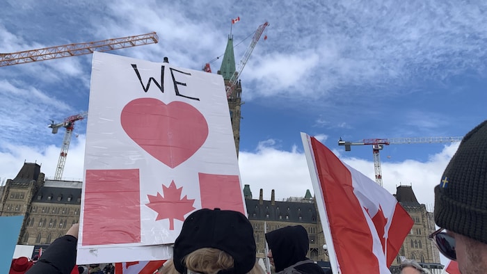 Une pancarte sur lequel on peut lire «On aime le Canada» avec le parlement en arrière-plan.