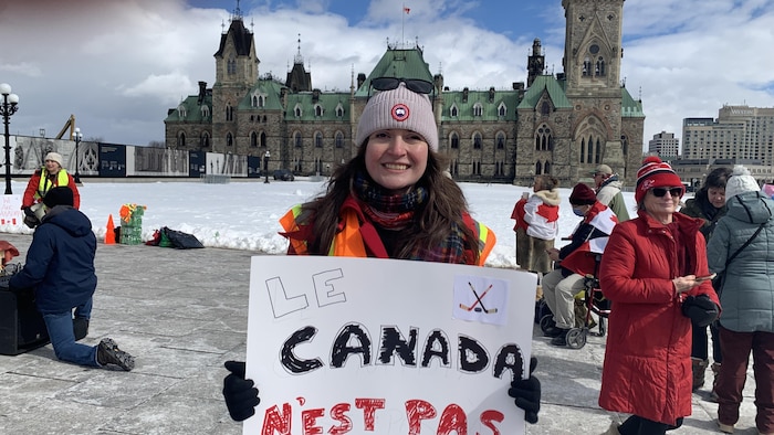 Portrait de Samantha McBeth qui tient une pancarte sur laquelle il est écrit «Le Canada n'est pas à vendre», sur la colline du Parlement.
