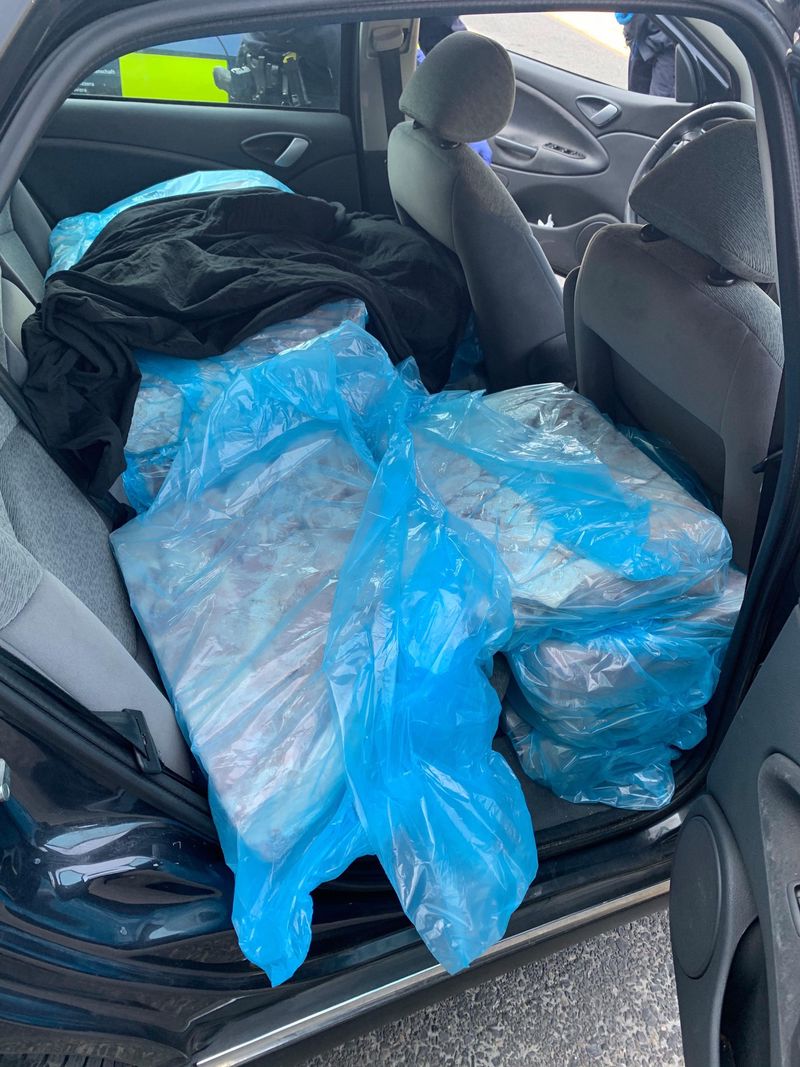 Des sacs bleus en plastique contiennent des objets non identifiés sur la banquette arrière d’une voiture.