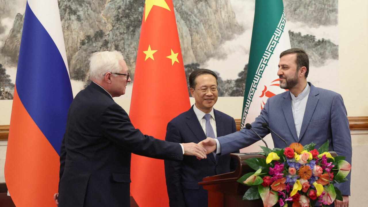 Le Russe Sergei Ryabkov, et l'Iranien Kazem Gharibabadi, se serrent la main sous le regard du Chinois Ma Zhaoxu, le 14 mars 2025 à Pékin.