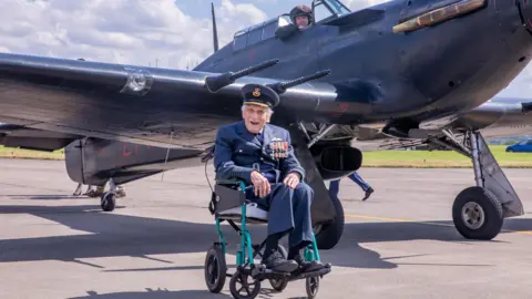 John 'Paddy' Hemingway en fauteuil roulant sur une piste d'atterrissage près d'un jet de la RAF.