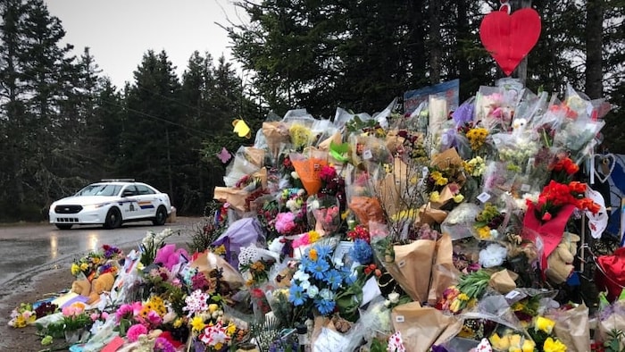 Une voiture de la GRC près d'une exposition commémorative à Portapique après la fusillade de masse en avril 2020.