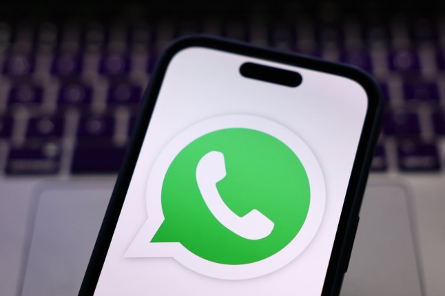 Clavier d'ordinateur portable et logo WhatsApp affiché sur un écran de téléphone