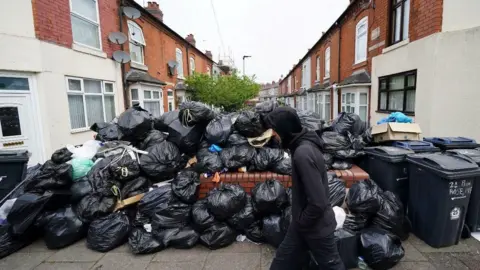 Montagne de sacs poubelle noirs empilés sur un mur dans une rue résidentielle à Birmingham