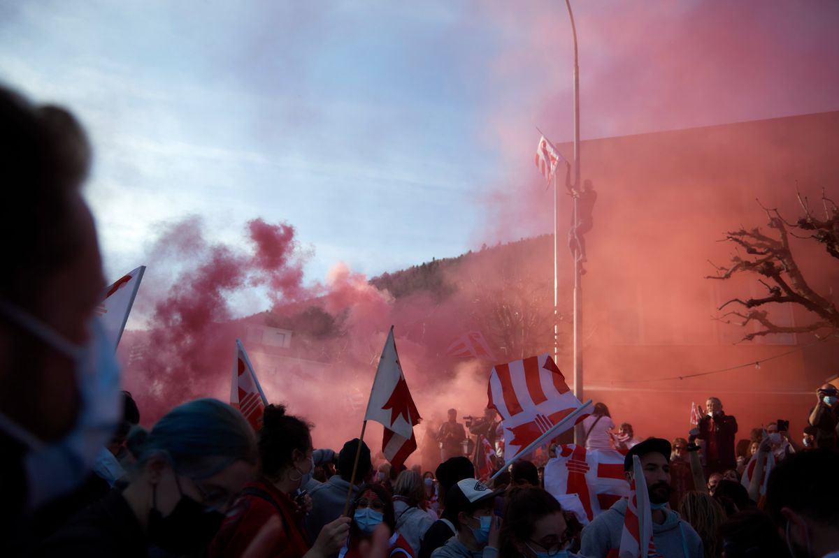 Foule célébrant avec des drapeaux et fumée rouge lors de l’annonce des résultats du vote sur l’appartenance cantonale de Moutier.