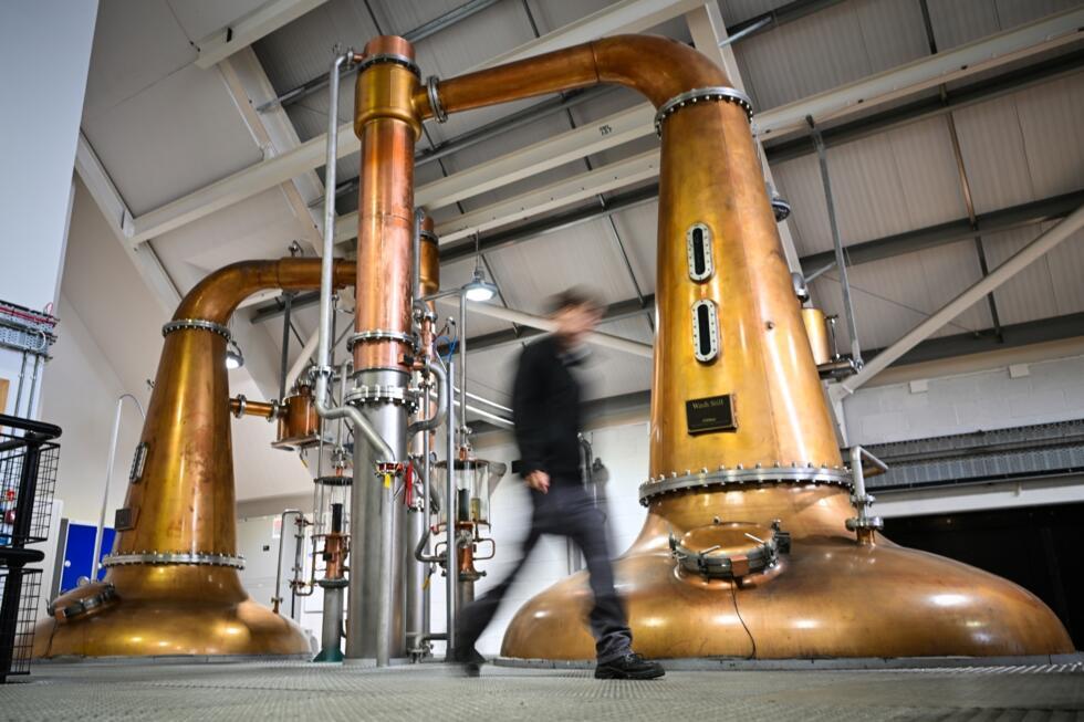 Donald MacRae passe devant un réservoir à la distillerie de l'île de Harris à Tarbert, le 28 avril 2025 en Ecosse