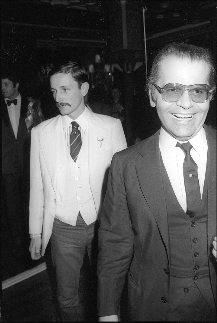 Jacques De Bascher et Karl Lagerfeld lors d’un événement en France, 1978. Lagerfeld souriant porte des lunettes.