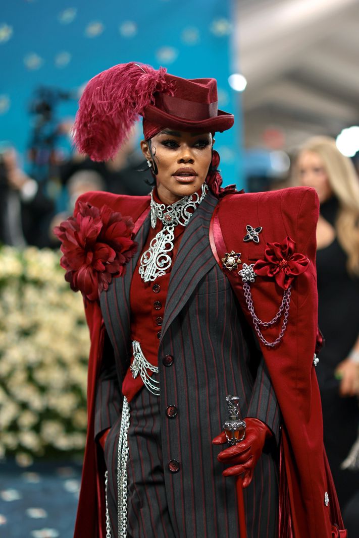 Teyana Taylor au Met Gala 2025, portant un costume rayé rouge avec plumes et broderies, au Metropolitan Museum of Art de New York.