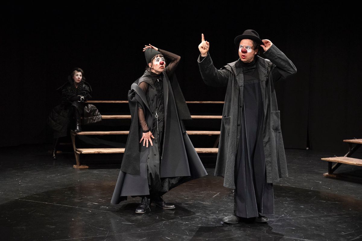 Acteurs sur scène en costumes noirs, interprétant une scène théâtrale comique.