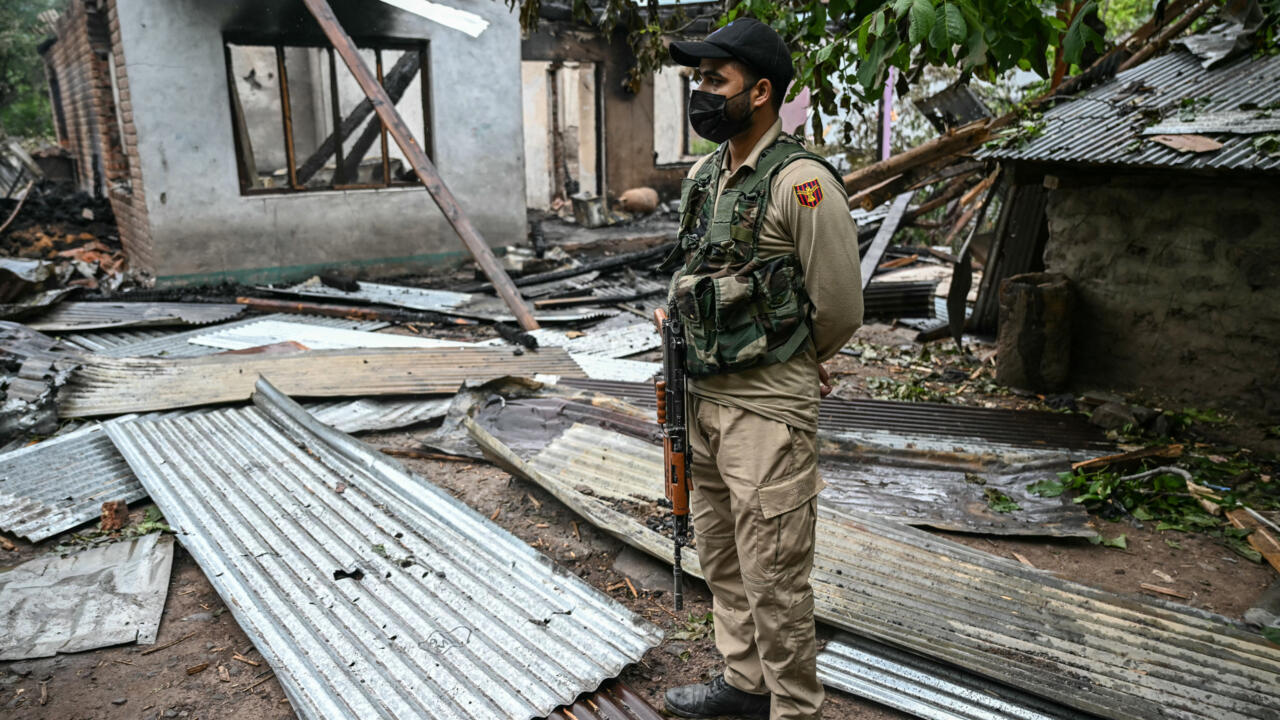 Un membre des forces de sécurité devant une maison détruite par des tirs d'artillerie pakistanais, dans le village indien de Salamabad, le 8 mai 2025.