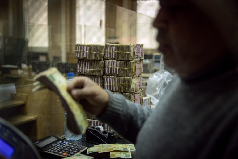 Employé devant des piles de livres syriennes à la Banque centrale de Syrie à Damas