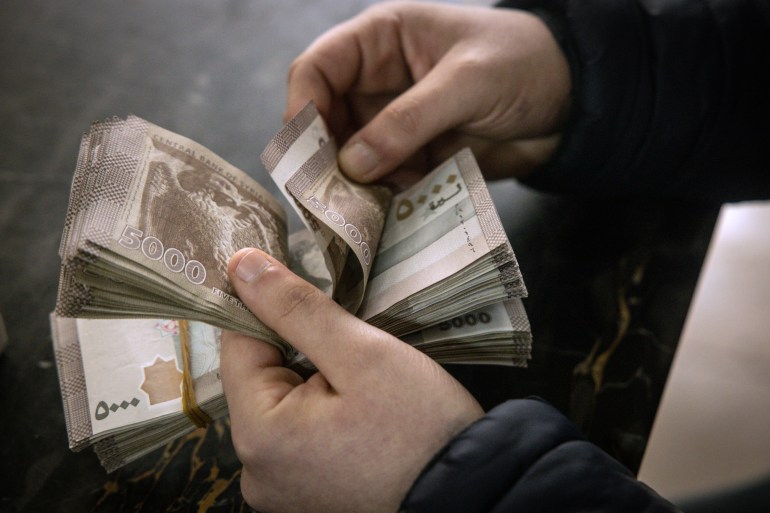 Un homme compte des livres syriennes après un échange de dollars américains à la Banque centrale de Syrie