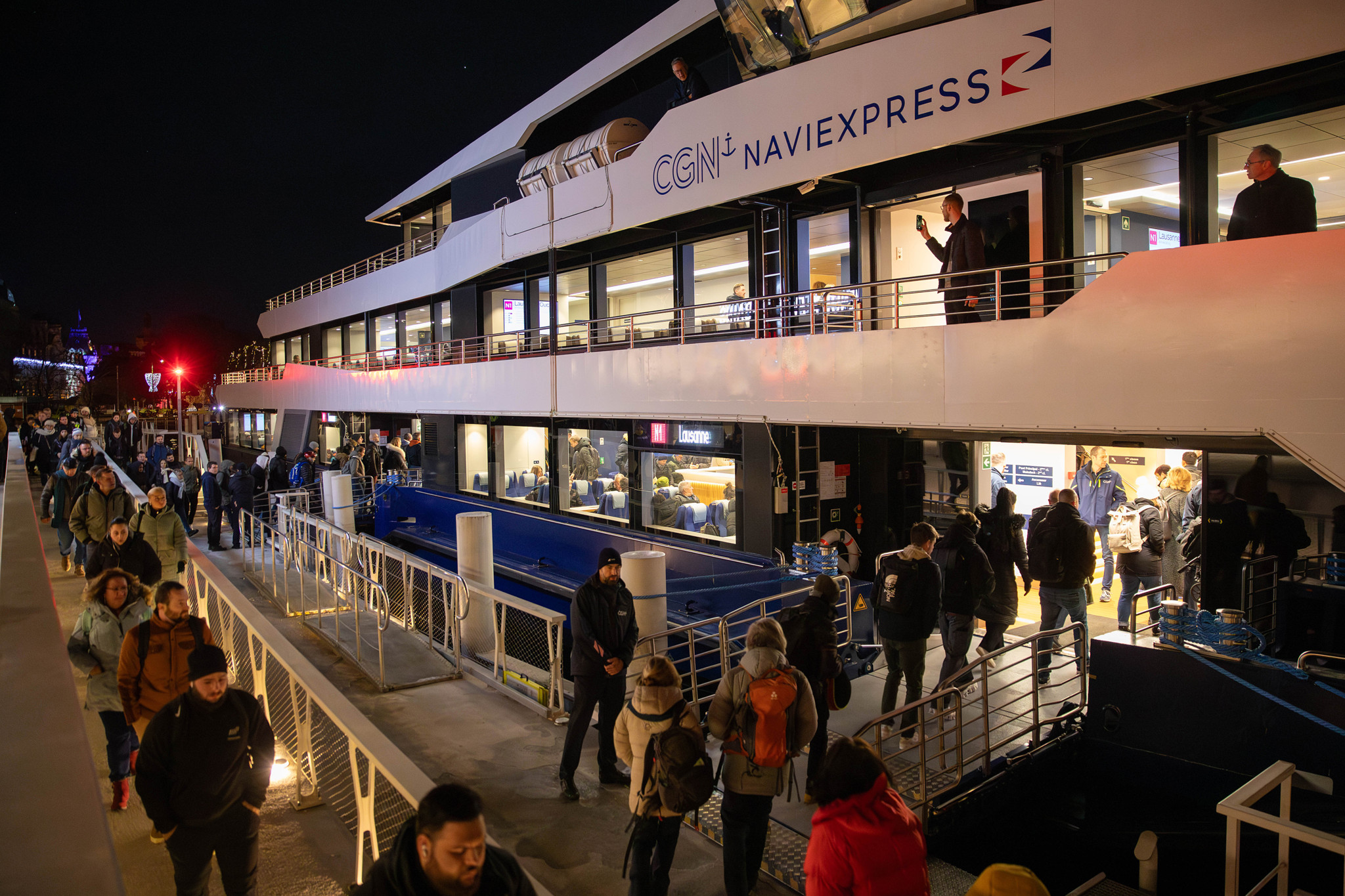 Passagers embarquant sur le nouveau bateau Naviexpress de la CGN pour le trajet entre Évian et Lausanne de nuit.