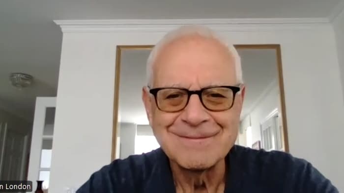 Ian London en entrevue dans son salon assis devant un miroir accroché sur un mur.