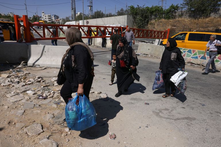 Palestiniens portant leurs affaires à pied, barrières en fer en Cisjordanie