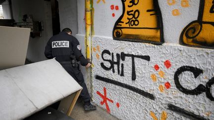 Un policier cherche de la drogue cachée sur un point de deal, le 1er décembre 2023 à Marseille (Bouches-du-Rhône). (NICOLAS TUCAT / AFP)