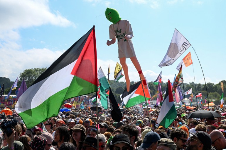 Fêtards brandissant drapeaux palestiniens et autres, lors du concert du groupe Kneecap au festival Glastonbury 2025, Royaume-Uni.