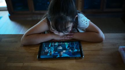 Une enfant regarde une tablette
